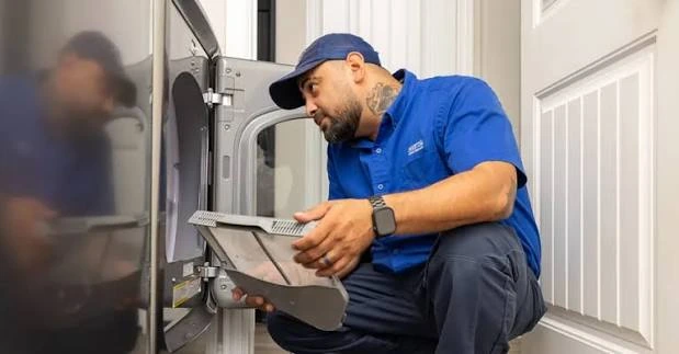 Technician inspecting a clothes dryer vent and filter assembly