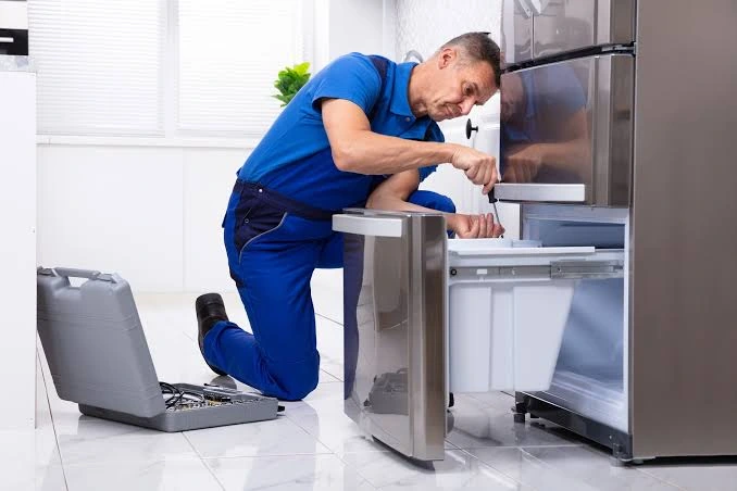 Technician adjusting an open refrigerator freezer drawer