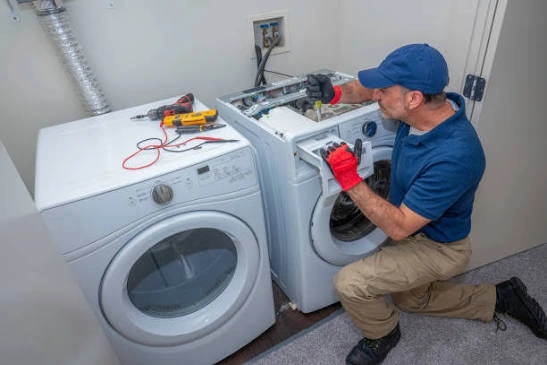 Technician working on a front-loading washer next to a dryer