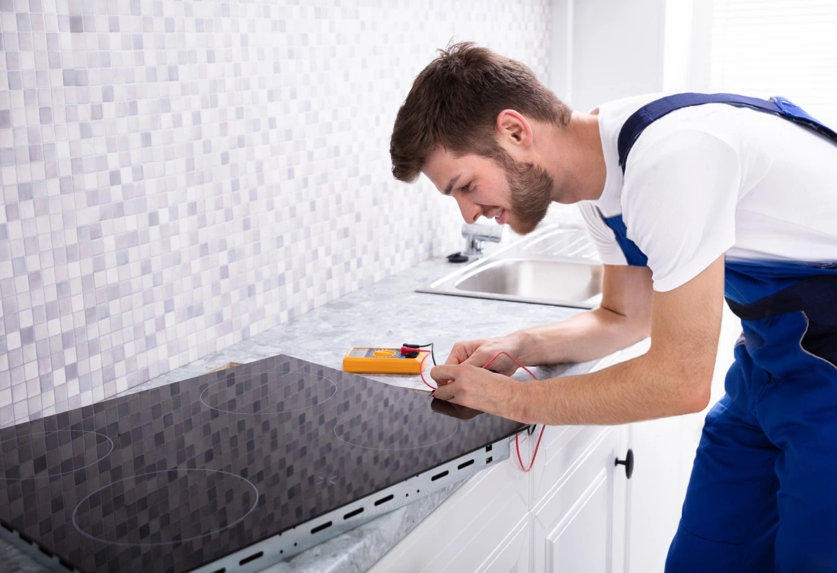 Technician checking an electric cooktop using a multimeter